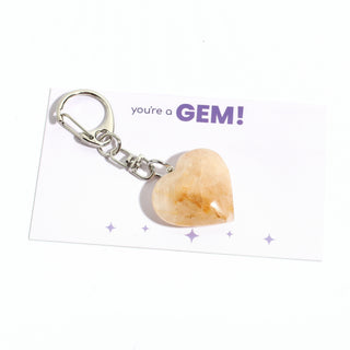 One of the five peach-gold golden healer heart charms from the pack, shown on its "you're a GEM!" gift backing card, hanging from its silver clasp on a clean white background. Stonebridge Imports.