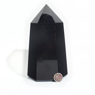 Black Obsidian Generator Unique #3 — polished six-sided tower with a faceted point, beside a Canadian dime for scale, photographed on a clean white background. Stonebridge Imports.