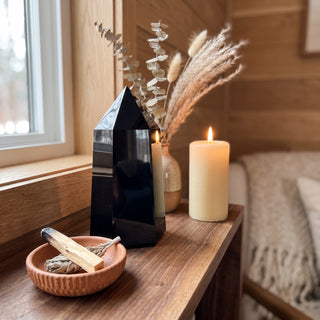 Black Obsidian Generator Unique #4 displayed on a wooden home altar shelf beside a lit candle and dried botanicals, shown at true size in warm natural light.