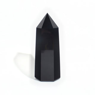 Black Obsidian Generator Unique #10 — polished six-sided tower rising to a faceted point, glossy jet-black faces, photographed on a clean white background. Stonebridge Imports.