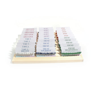 Front view of the Intention Bracelet Display Kit: a slanted pine counter stand holding 30 carded amethyst, rose quartz, howlite, carnelian, sodalite and green aventurine bracelets, on white. Stonebridge Imports.