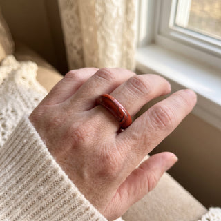 Red Jasper Ring worn on the hand in natural light, showing the solid brick-red red jasper band at true scale.