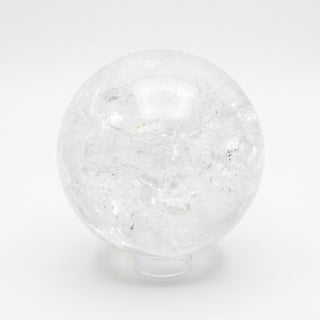 Clear Quartz Sphere Unique #19 - 6", a polished clear quartz sphere on a clear display stand shown from an alternate angle on a clean white background. Stonebridge Imports.