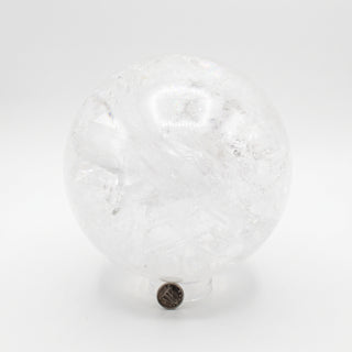 Clear Quartz Sphere Unique #19 - 6", a polished clear quartz sphere on a clear display stand shown from an alternate angle on a clean white background. Stonebridge Imports.