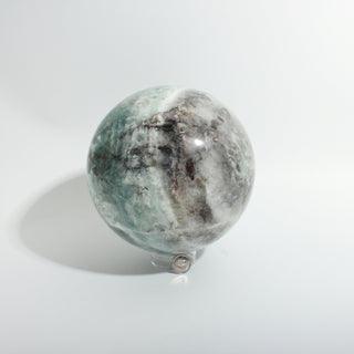 Fluorite Green and Purple Sphere Unique #9, alternate angle showing translucent sea-green fluorite with white and grey veining, on a clean white background. Stonebridge Imports.