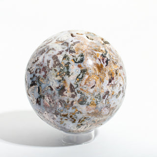 Close-up of Sea Jasper Sphere Unique #1, showing the detail of its tan, dark brown and sea-green orbs against pale blue-grey chalcedony, photographed on a clean white background. Stonebridge Imports.