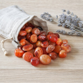 Carnelian Light Tumbled Stones - South Africa spilling from a linen pouch