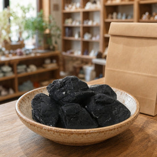 Black Tourmaline Tumbled Stones A - Free Form - 1lb in a ceramic bowl on a shop counter