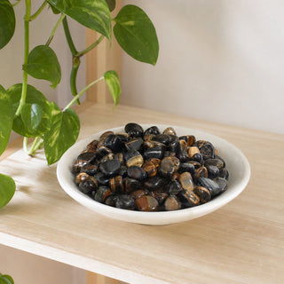 Blue and Gold Tiger Eye Tumbled Stones in a stoneware dish on a shop shelf