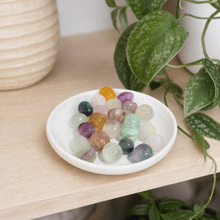 Candy Fluorite B Tumbled Stones in a stoneware dish on a shop shelf