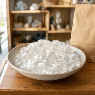 Clear Quartz E Tumbled Stones in a ceramic bowl on a shop counter