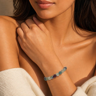 Fluorite bead bracelet worn with the fingertips resting at the collarbone