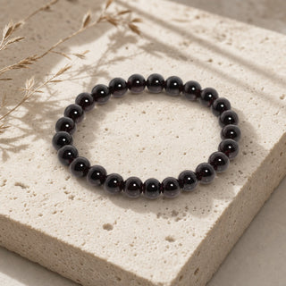 Garnet bead bracelet resting on a stone slab