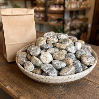 Granite Tumbled Stones - 16kg in a ceramic bowl on a shop counter