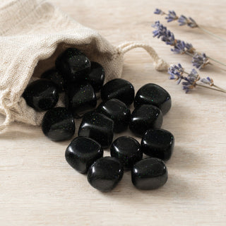 Green Goldstone Tumbled Stones (Synthetic) spilling from a linen pouch