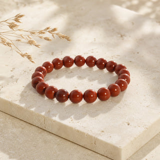 Red Jasper bead bracelet resting on a stone slab