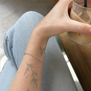 Labradorite bead bracelet worn on a tattooed forearm holding a coffee