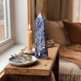 Sodalite Generator Unique #8 displayed on a wooden home altar shelf beside a candle, shown at true size in warm natural light.