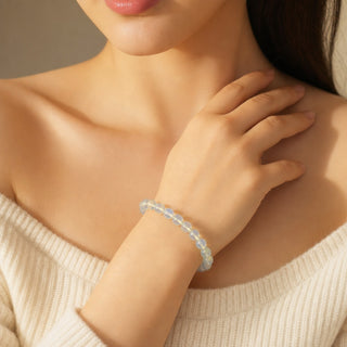 Opalite bead bracelet worn with the fingertips resting at the collarbone