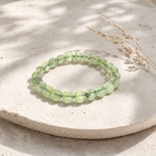 Prehnite bead bracelet resting on a stone slab