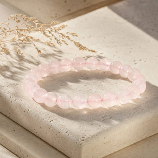 Rose Quartz bead bracelet resting on a stone slab