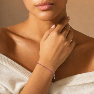 Ruby bead bracelet worn with the fingertips resting at the collarbone